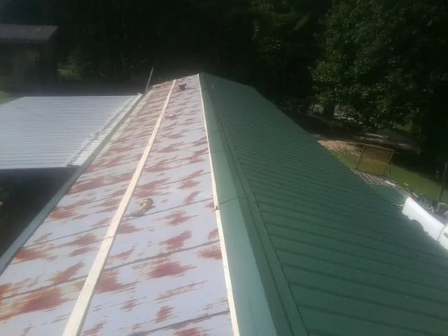 Old rusted panels beside newly installed green metal roofing — Wind Damage Roof Repair by Roofing Brothers in Kalispell