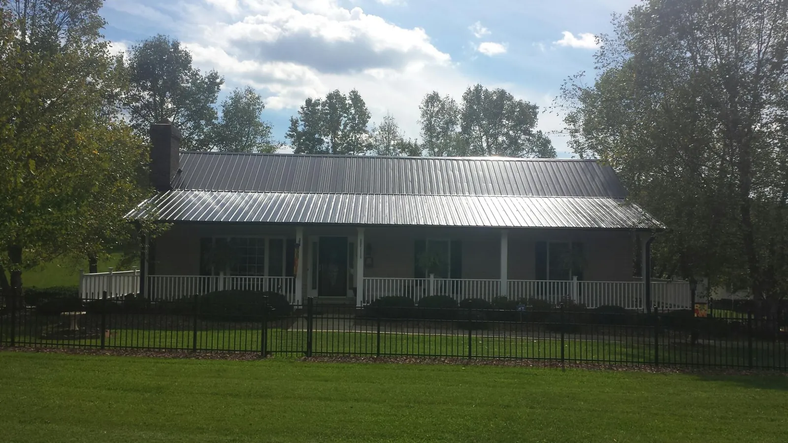 Gray metal roof on a brick ranch with a full width front porch — Gutter Guard Installation work by our crew in Kalispell